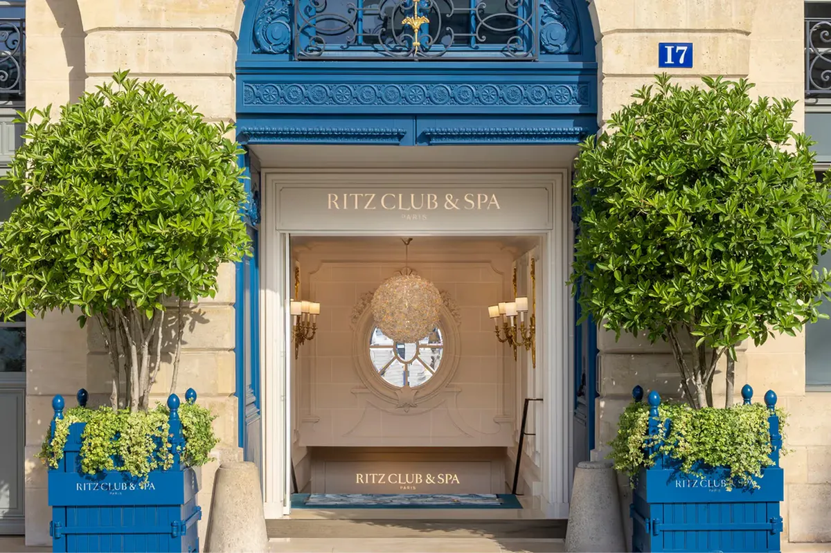 The Ritz Club & Spa entrance with blue door, topiary flanking, and street-level signage