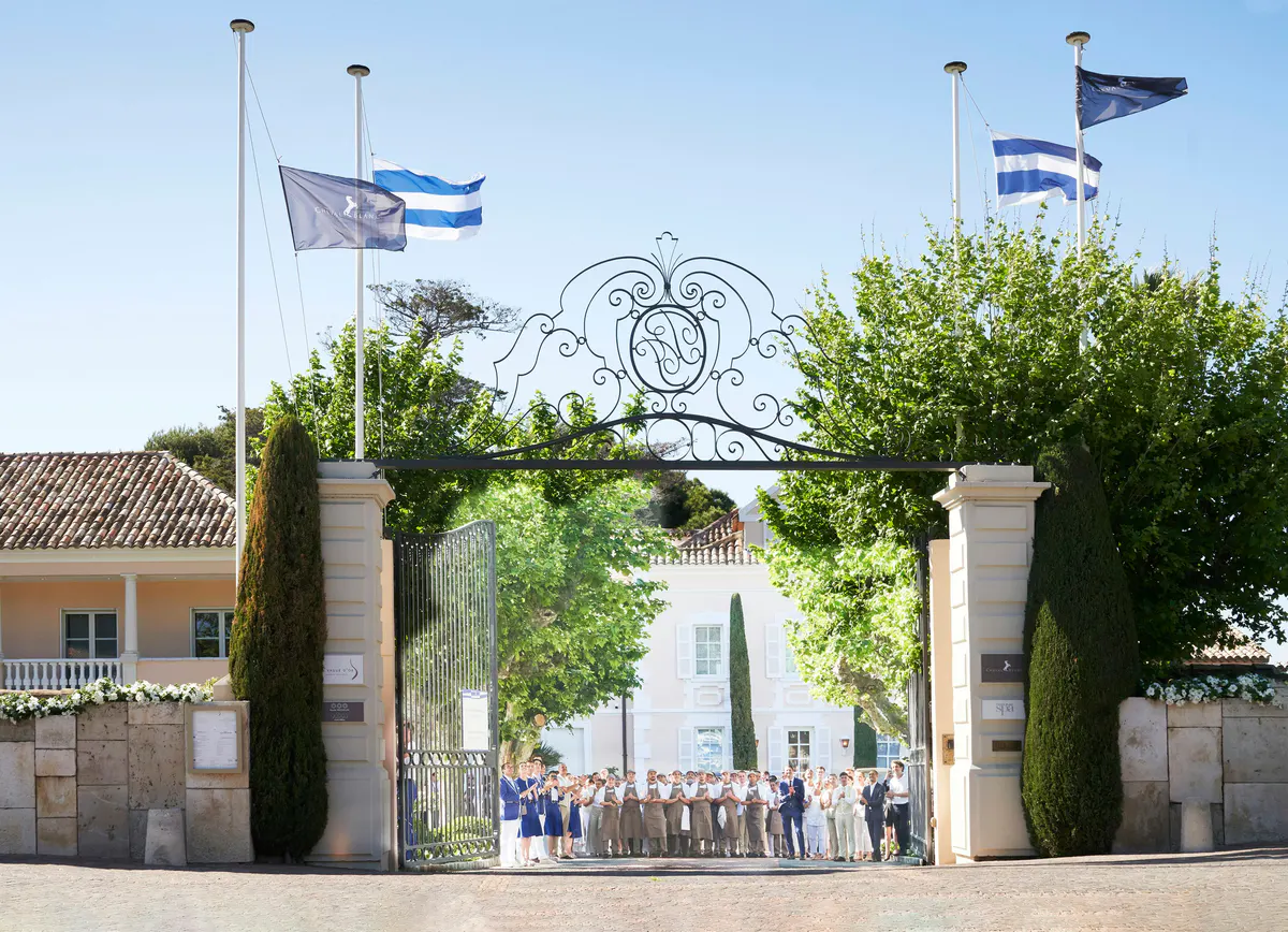 Ornate entrance gate with decorative sculpture and planted urns