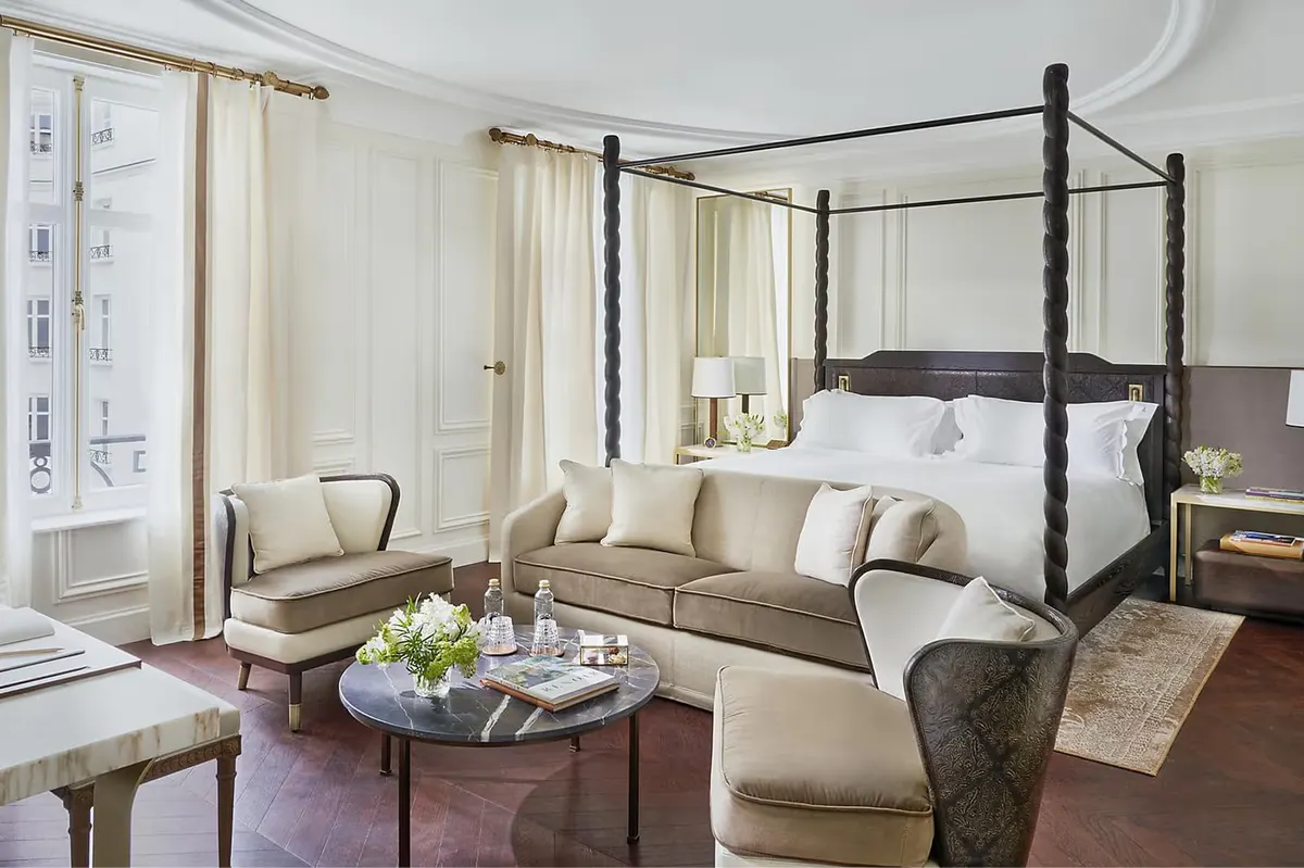 Guest bedroom with black four-poster bed, cream sofa, and wood coffee table