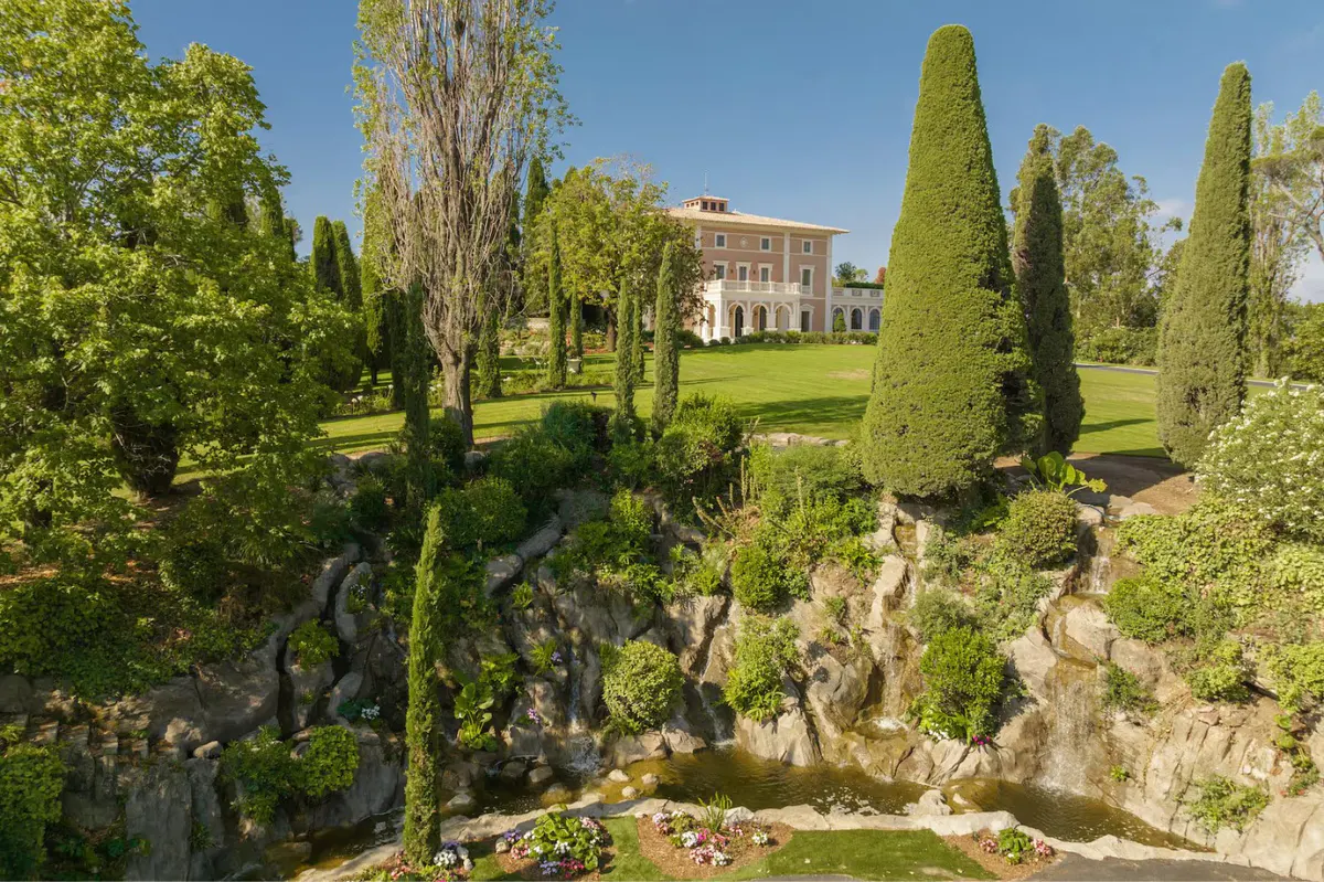 Garden grounds with cypress trees, ornamental urns, and distant château silhouette