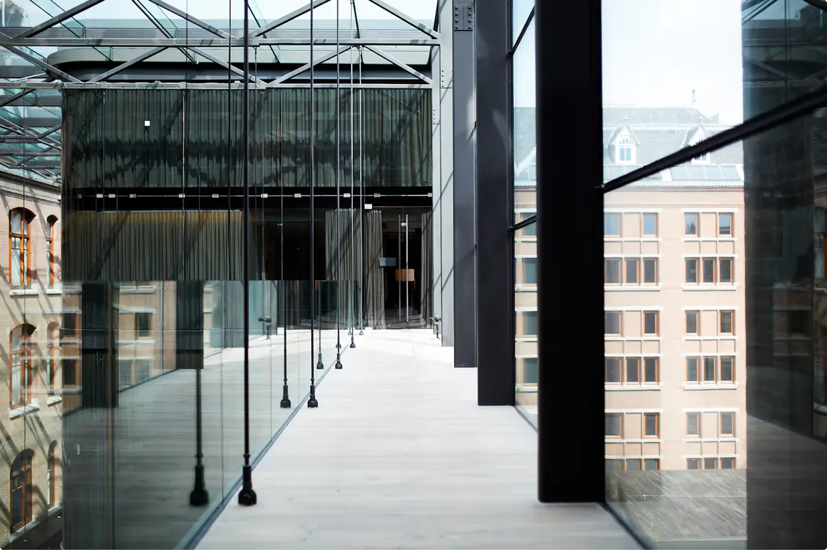 Modern rooftop terrace with floor-to-ceiling glass panels, dark columns, and city views