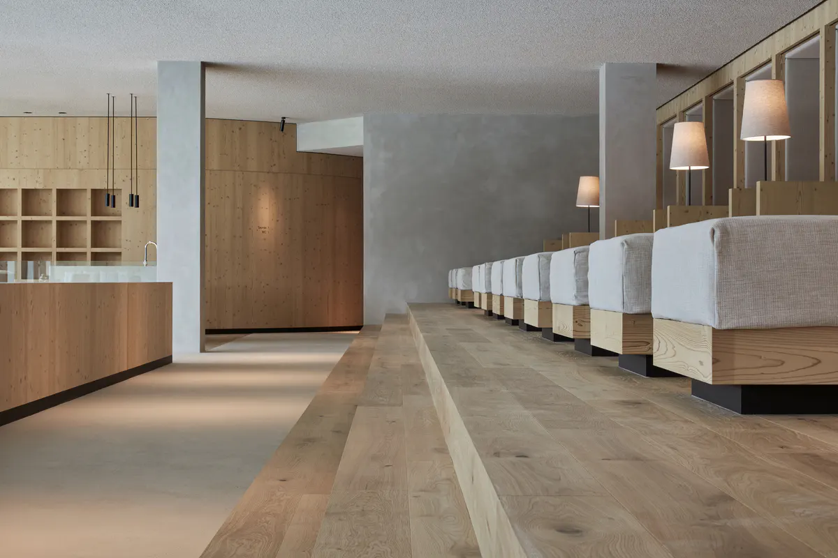 A spa corridor with wooden and concrete finishes, lit by soft side lighting, lined with natural materials