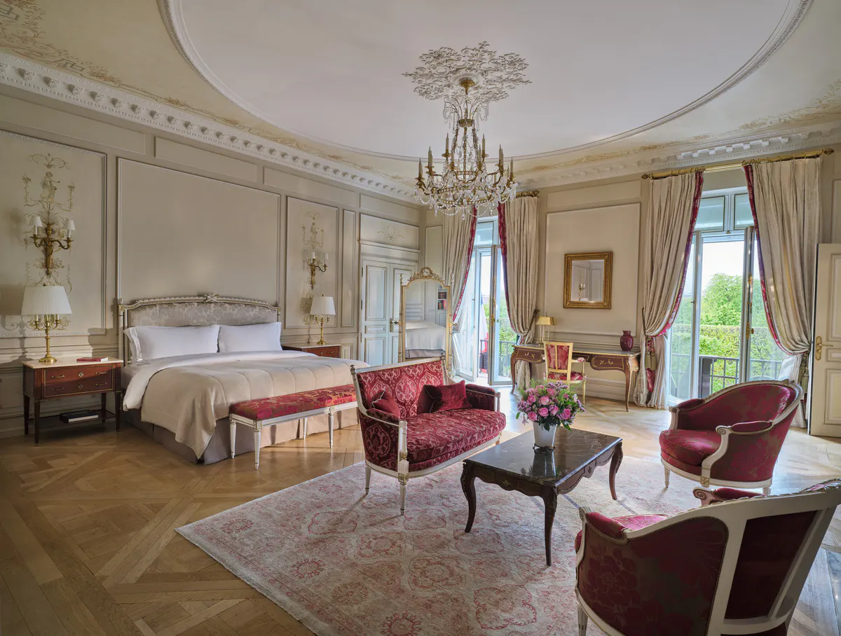 A grand suite with queen bed, velvet upholstery, chandelier, and ornate ceiling details