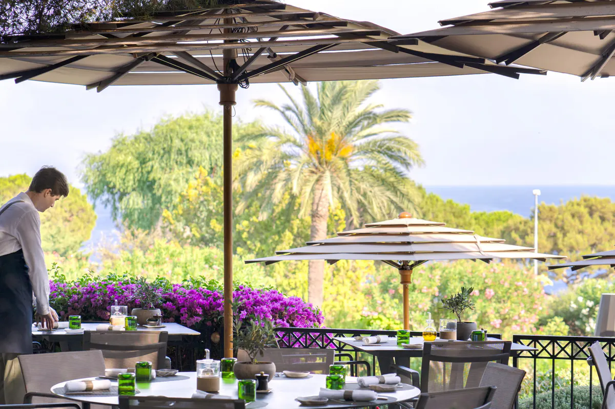 Shaded deck area with umbrella and sea view above palm trees