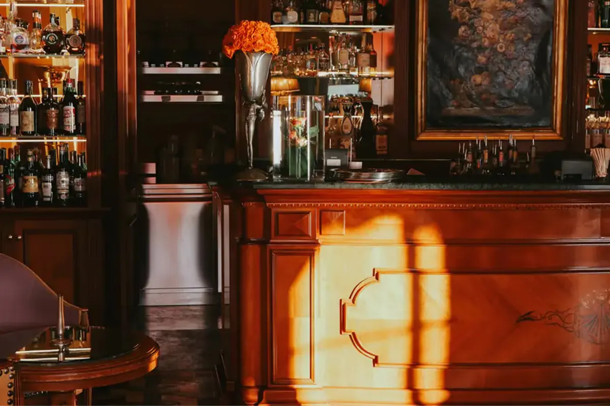 Bar area with wood cabinetry and shelves of bottles in warm light