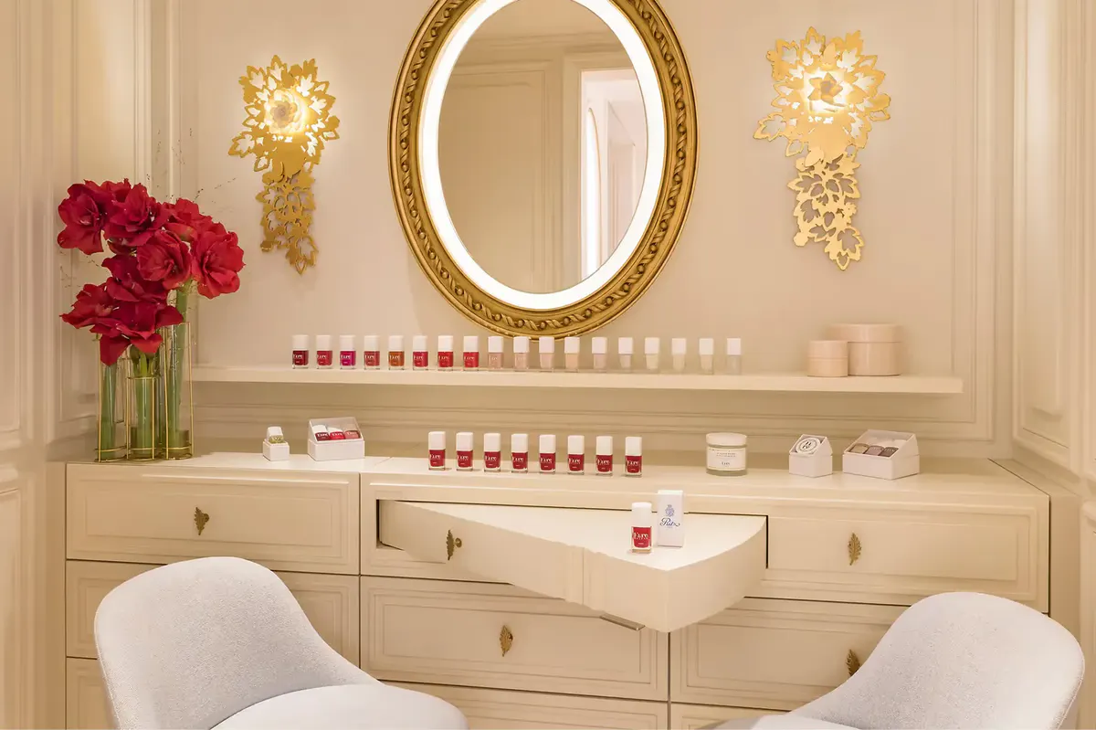A spa treatment room with round mirror, cream furnishings, and pink floral accent