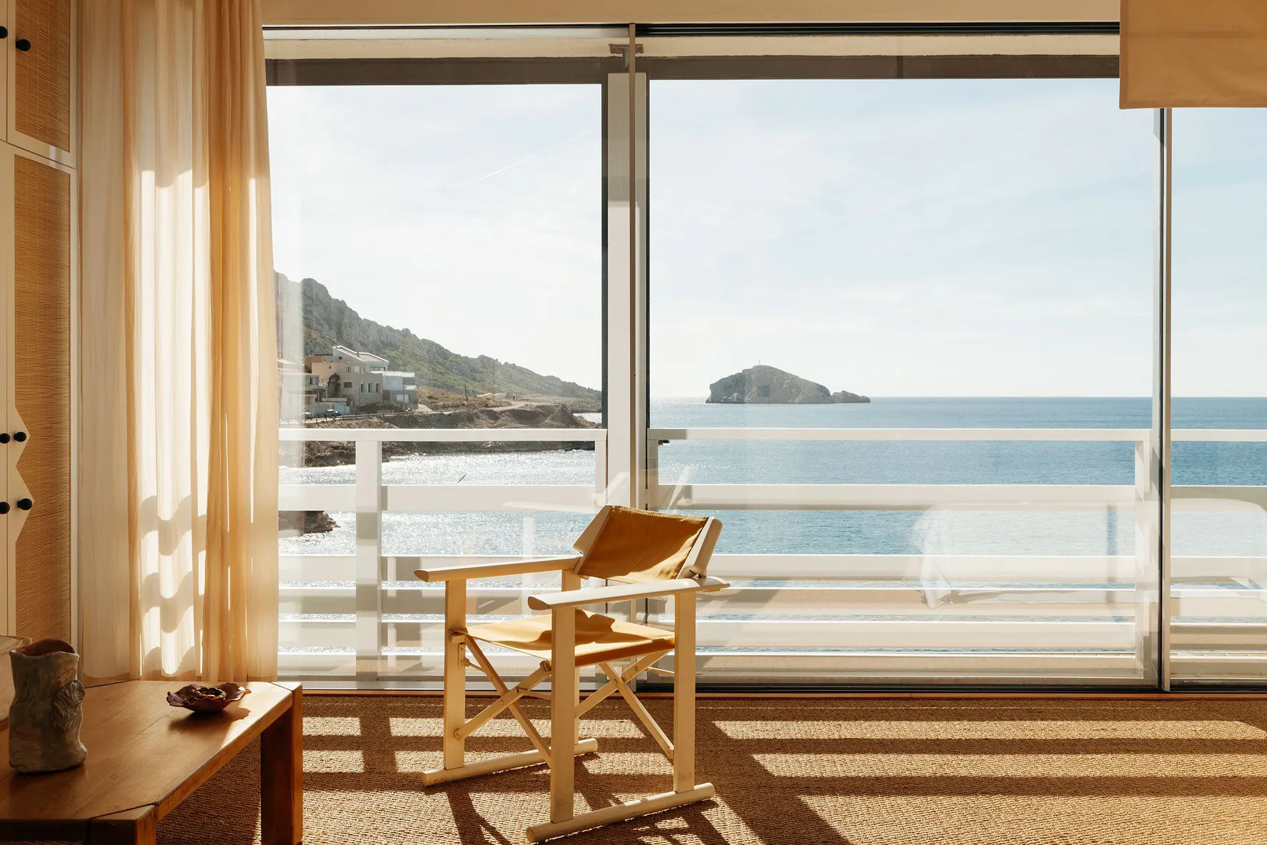 A cabanon at Tuba Club, a canvas chair facing the sea through open glass