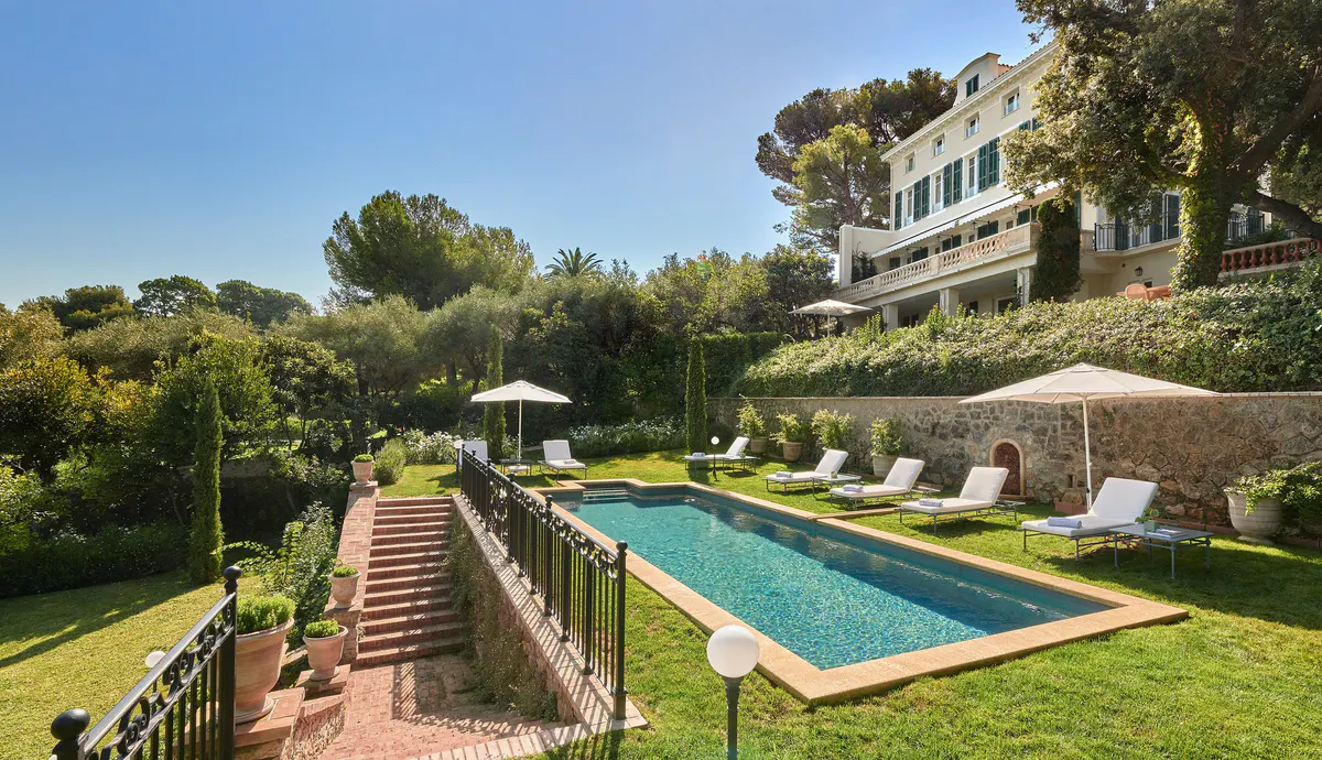 A private terraced garden with lounge seating, umbrellas, and views over the Mediterranean