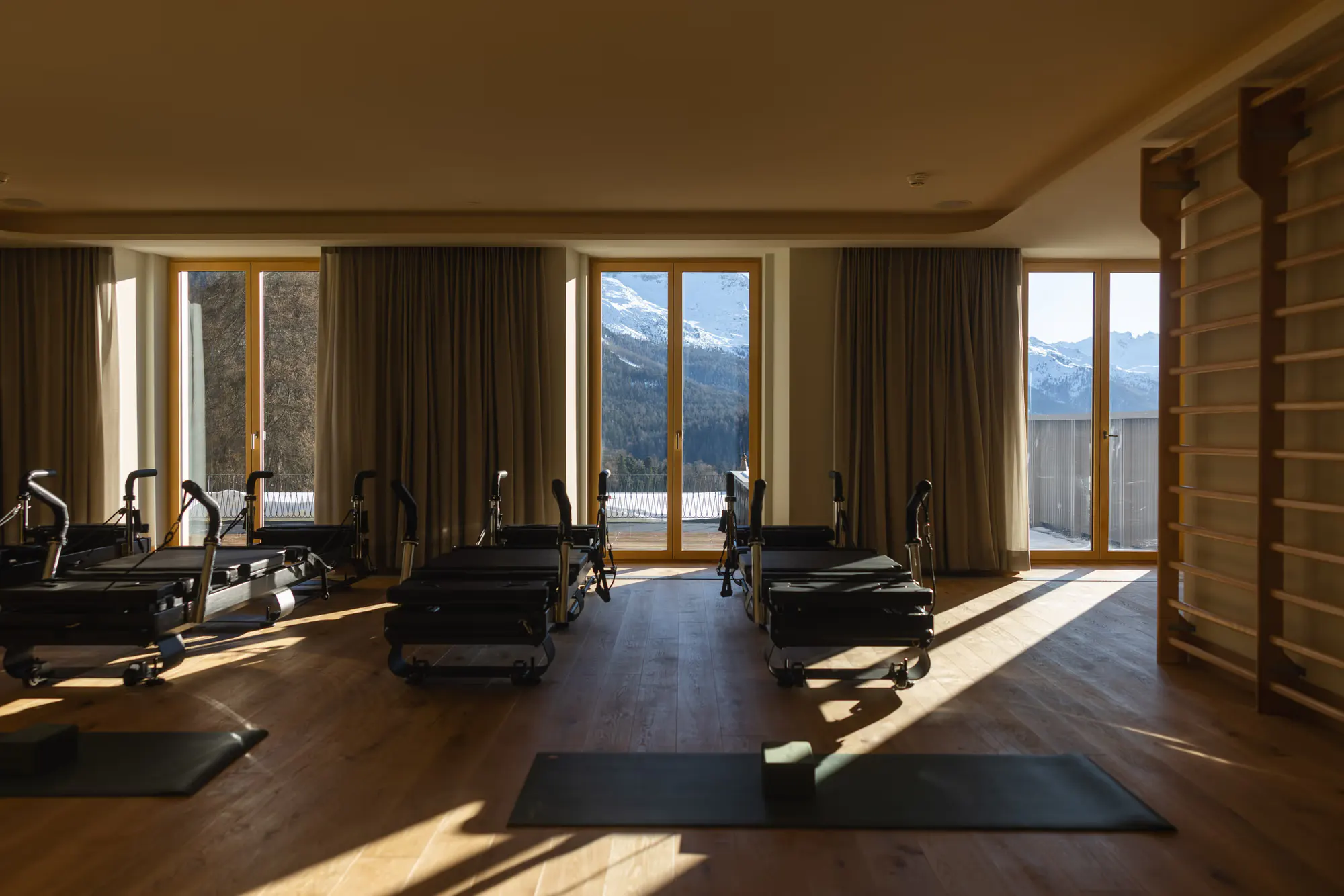 A pilates studio lined with reformers, mountain light in the windows
