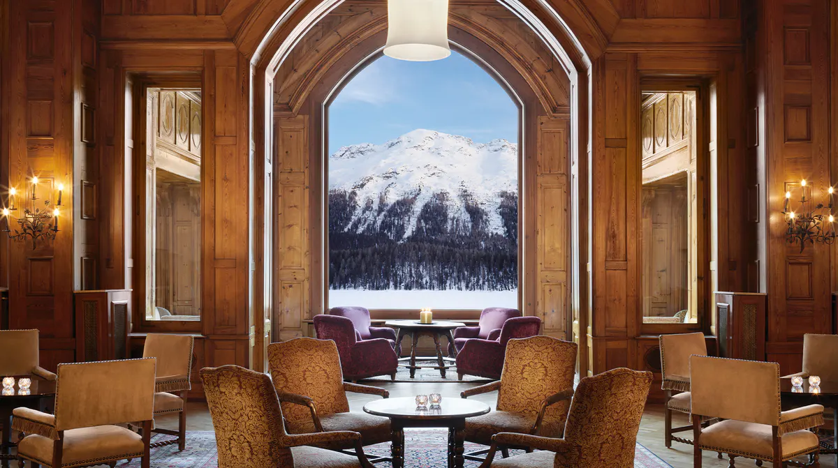 Wood-paneled lounge with arched doorway framing snow-capped mountain