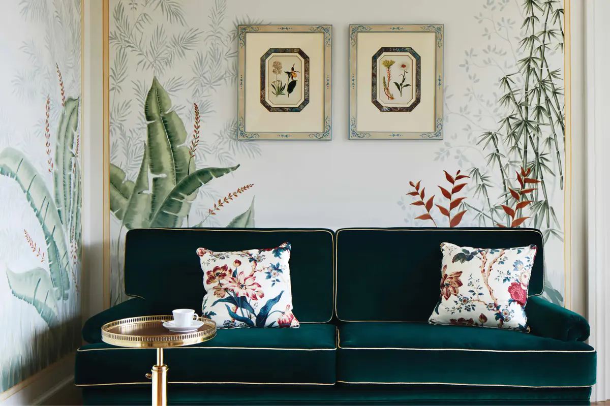 A suite interior featuring botanical wallpaper, green sofa, and sea-view glass doors