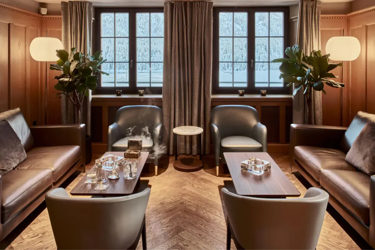 Wood-paneled sitting room with leather seating, side tables, lamps, and window views