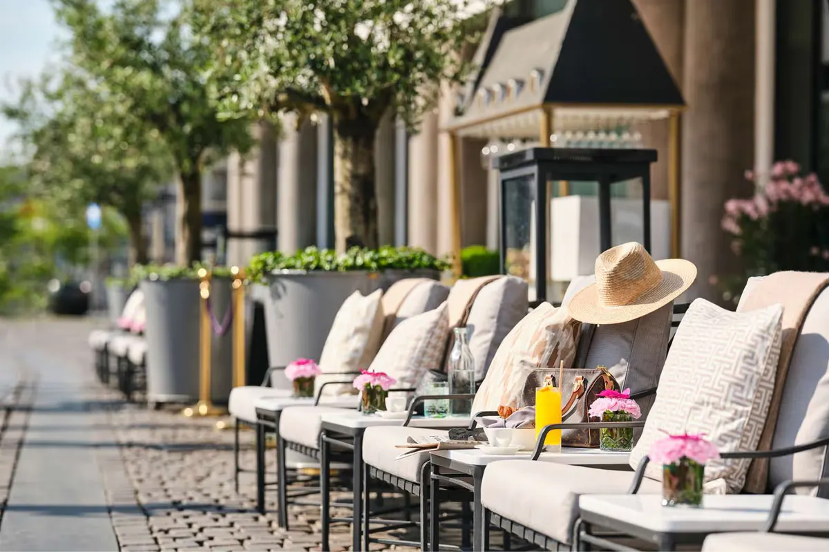 Sidewalk seating area with cushioned chairs and flowering planters