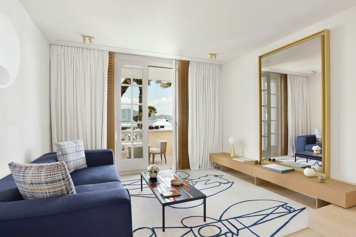 Light-filled suite with navy sofa, mirror, and terrace access