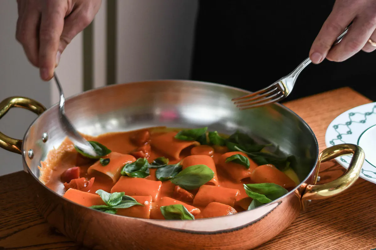 Pasta dish in copper pan with basil and red sauce