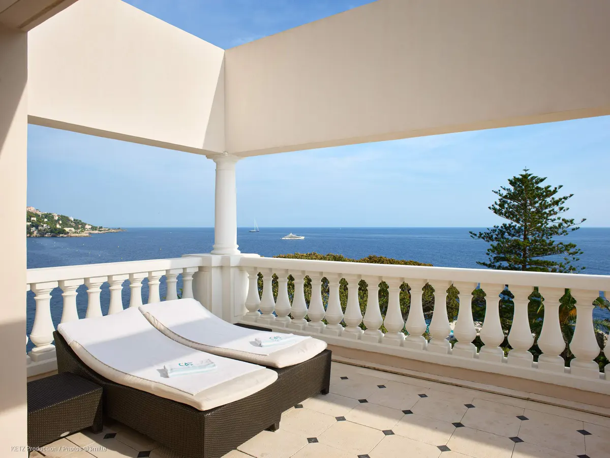 A sunbed on a stone terrace with balusters overlooking the Mediterranean