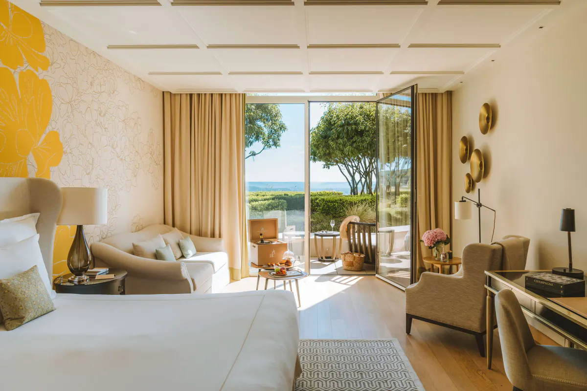 Modern suite with cream furnishings and glass doors opening to a terrace with valley views