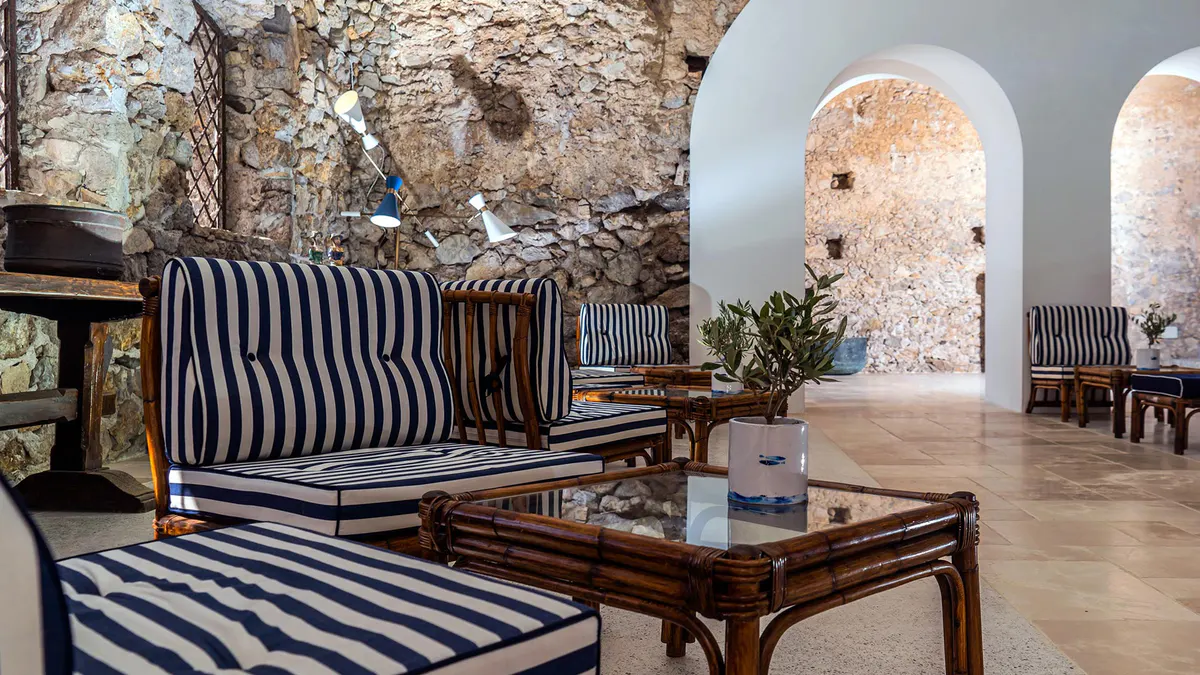 Lounge area with striped sofa, black coffee table, stone walls, and barrel vault ceiling