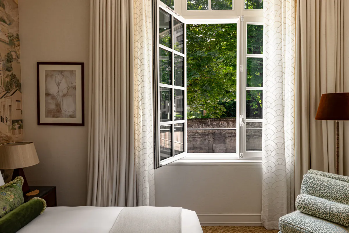Guest suite with cream furnishings, sash windows opening onto private garden terrace
