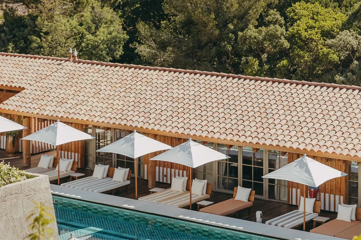 Pool area with cabanas and daybeds overlooking forested hillside