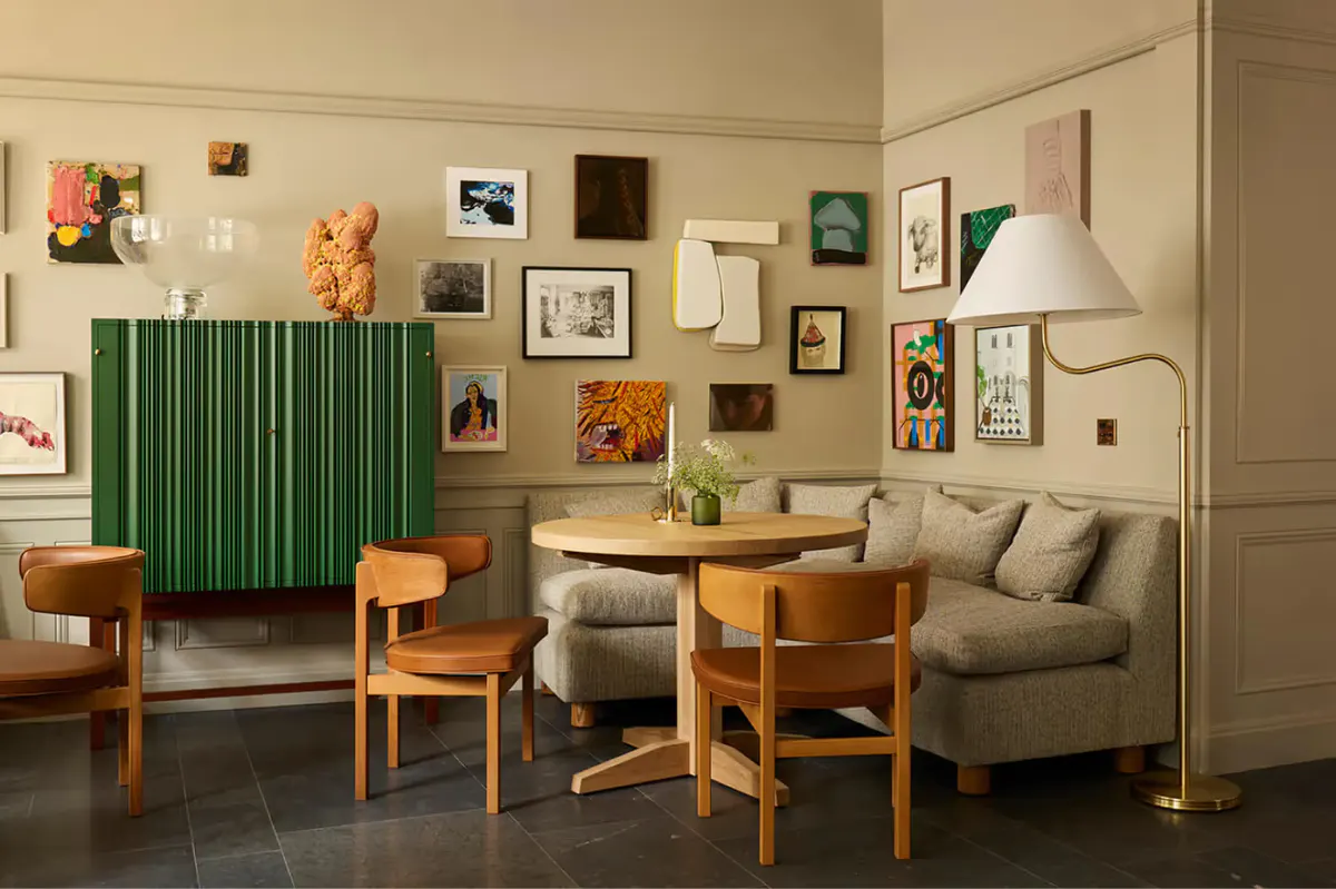 A lounge with green accent wall, wooden furniture, and wall-mounted artwork collection