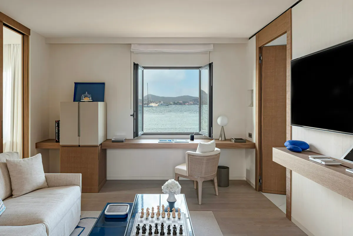 Contemporary suite with desk, white bed, and sea-view opening