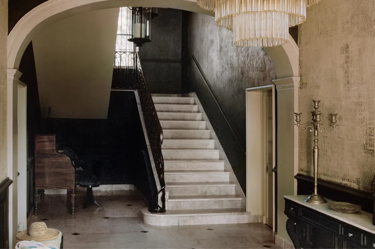 Barrel-vaulted stone hall with staircase, glass pendant, and minimalist modern furnishings