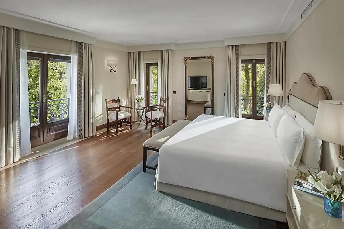 Spacious suite with multiple seating areas, wood accents, and floor-to-ceiling windows