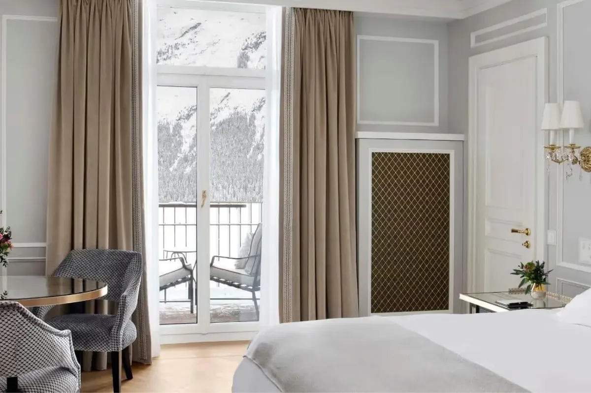 Bedroom with cream-colored walls, tall windows with valley views, tan curtains