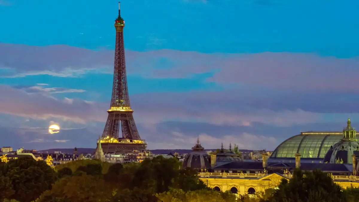 Illuminated Eiffel Tower visible through bedroom window at night