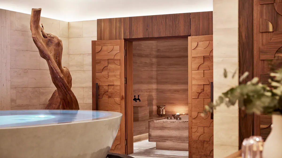 A spa with soaking tub, wooden steam room, and sculptural wooden element