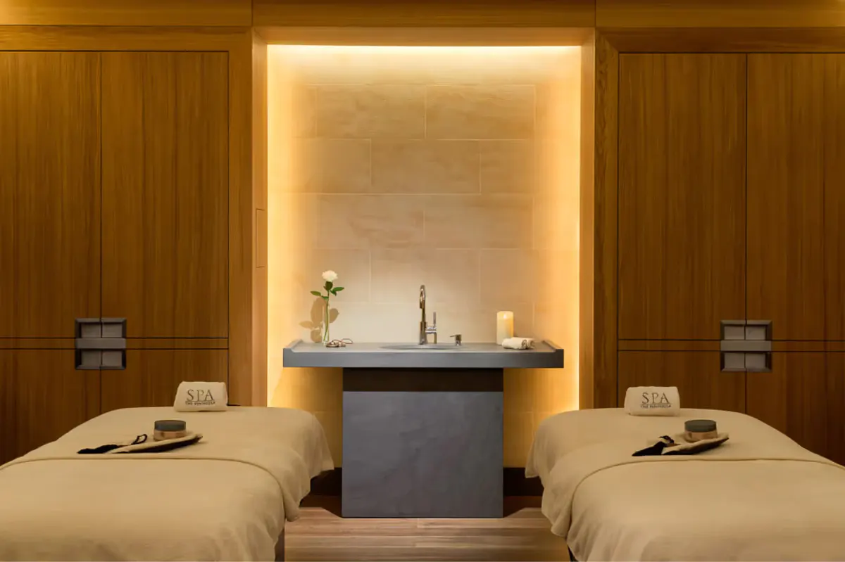 Spa relaxation room with warm wood, lounge seating, and framed coastal artwork