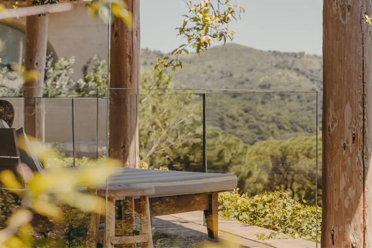 Desk beside large window with distant hills framed by wooden beams