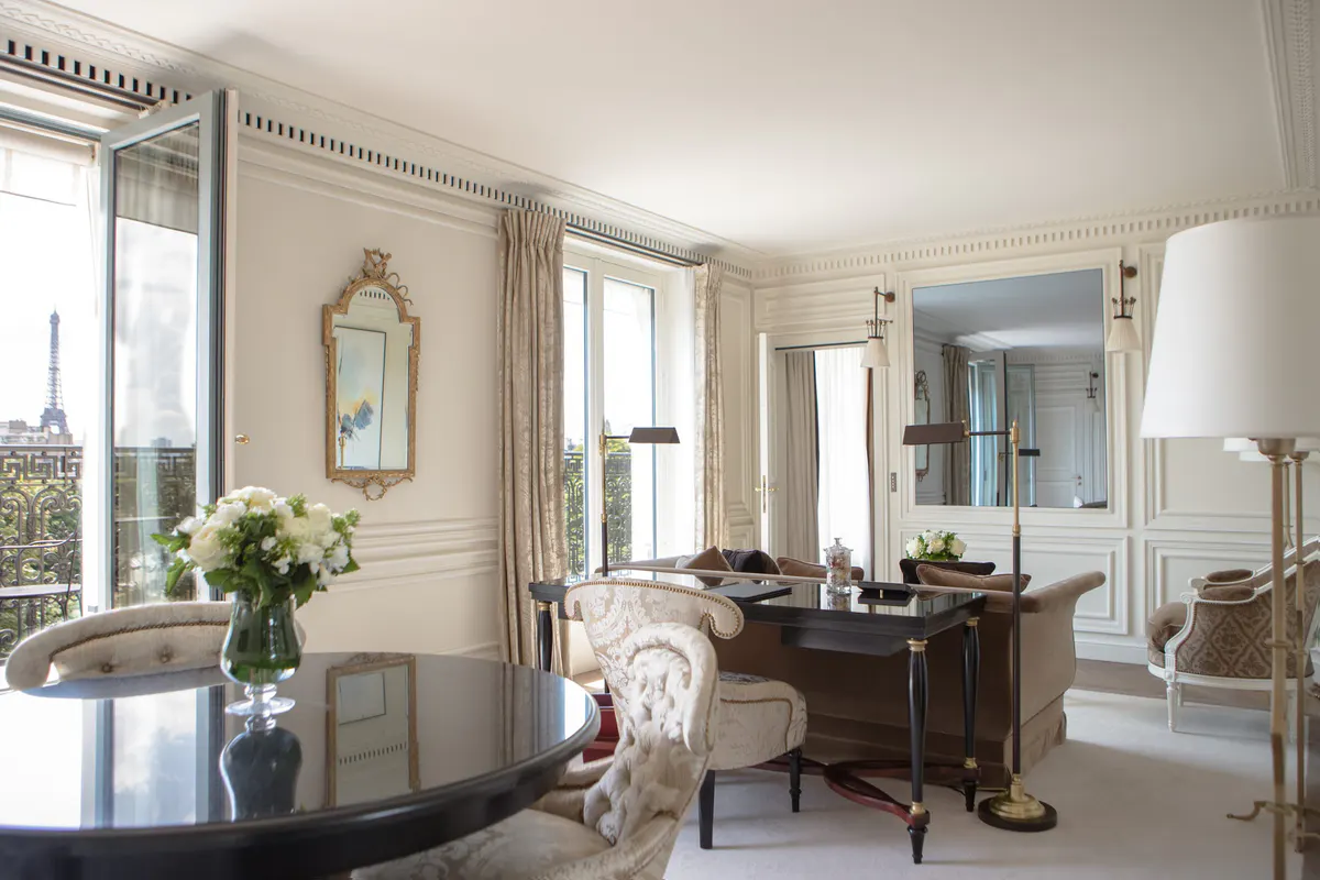 A sitting area with a writing desk, botanical accents, and floor-to-ceiling windows
