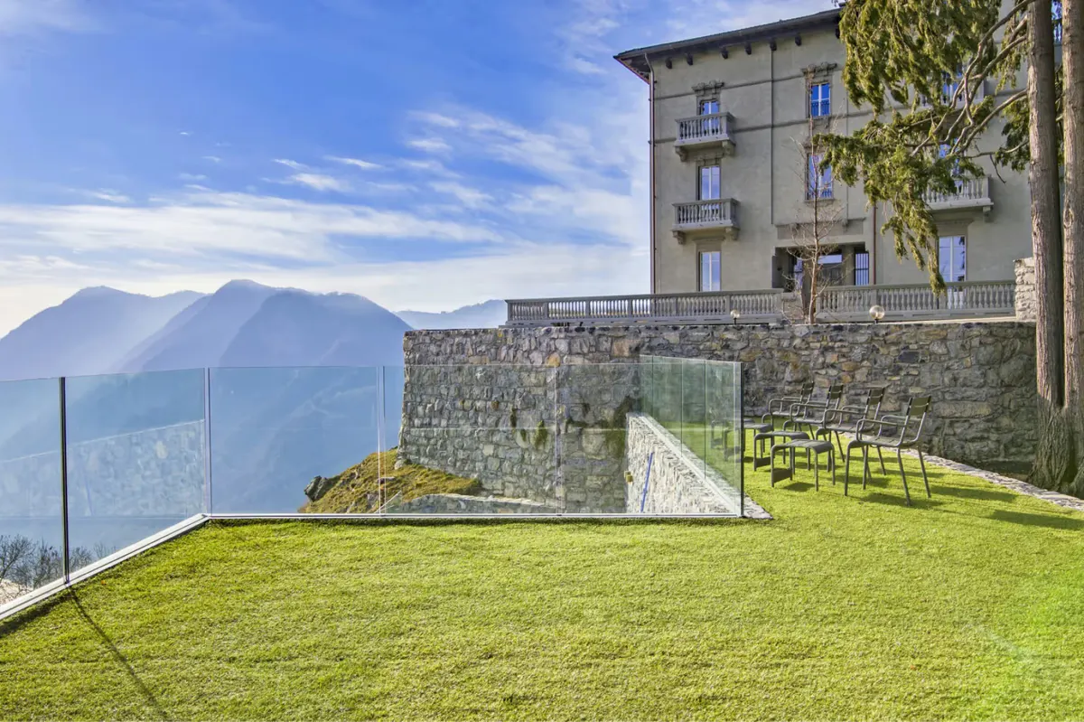 The villa grounds with manicured lawn overlooking the lake and surrounding peaks
