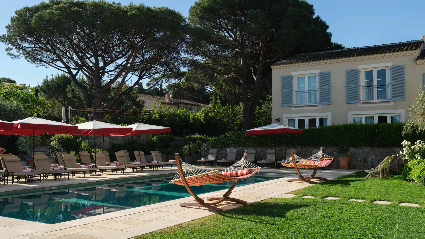 The pool at Lou Pinet with red umbrellas and pines behind
