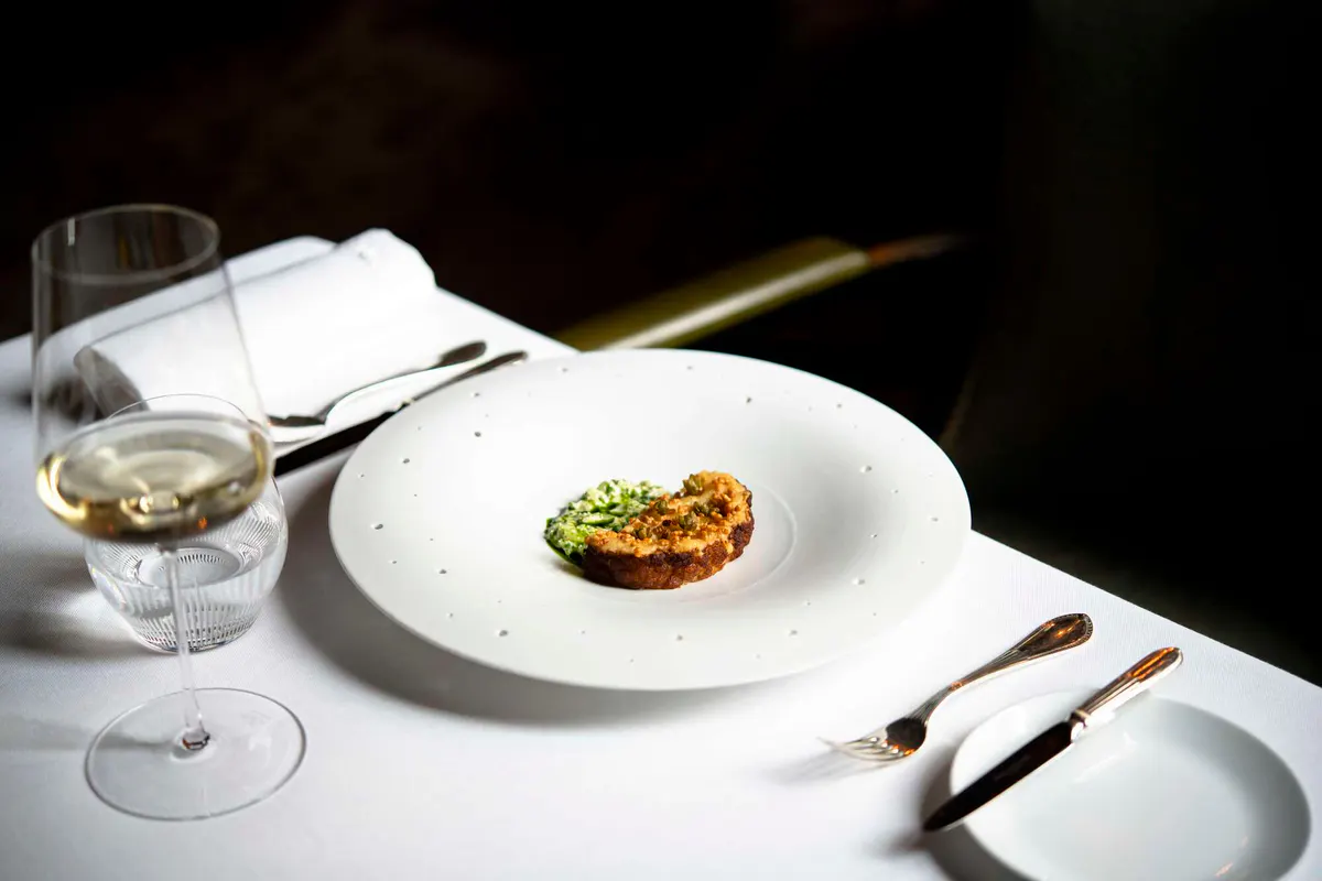 A fine dining plate with wine glass and formal place setting