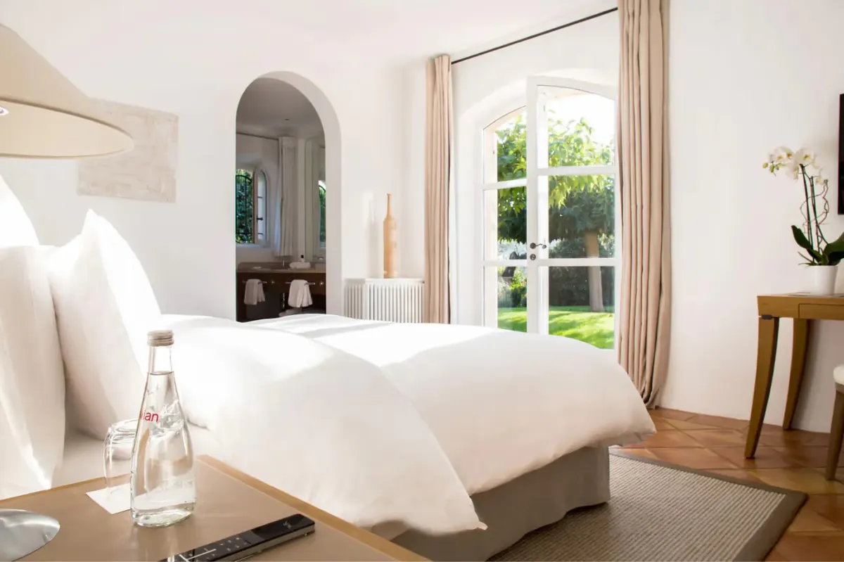 Minimalist white bedroom with arched doorway and garden view