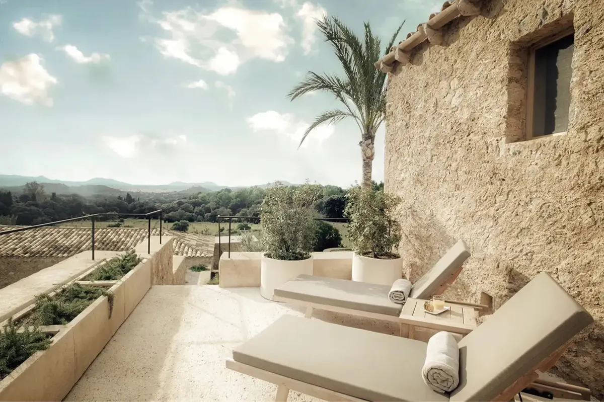 Outdoor terrace of restored stone casita with lounge seating, olive trees, and mountain vistas at dusk