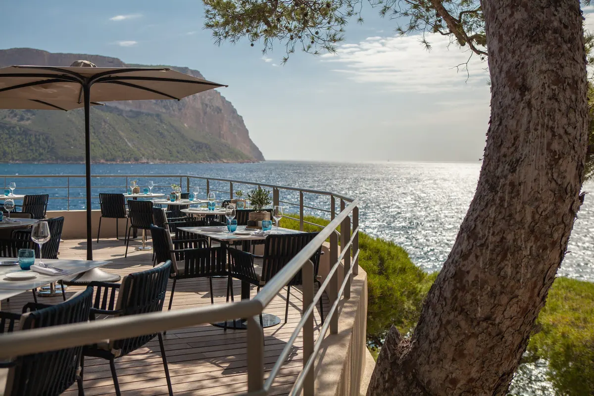 A seaside dining terrace with shaded seating area and Mediterranean views at the property