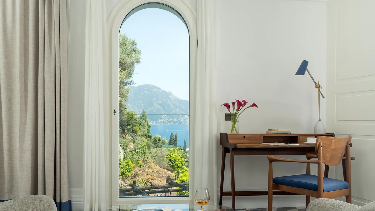 Suite with arched opening framing mountain and sea views, midcentury furnishings
