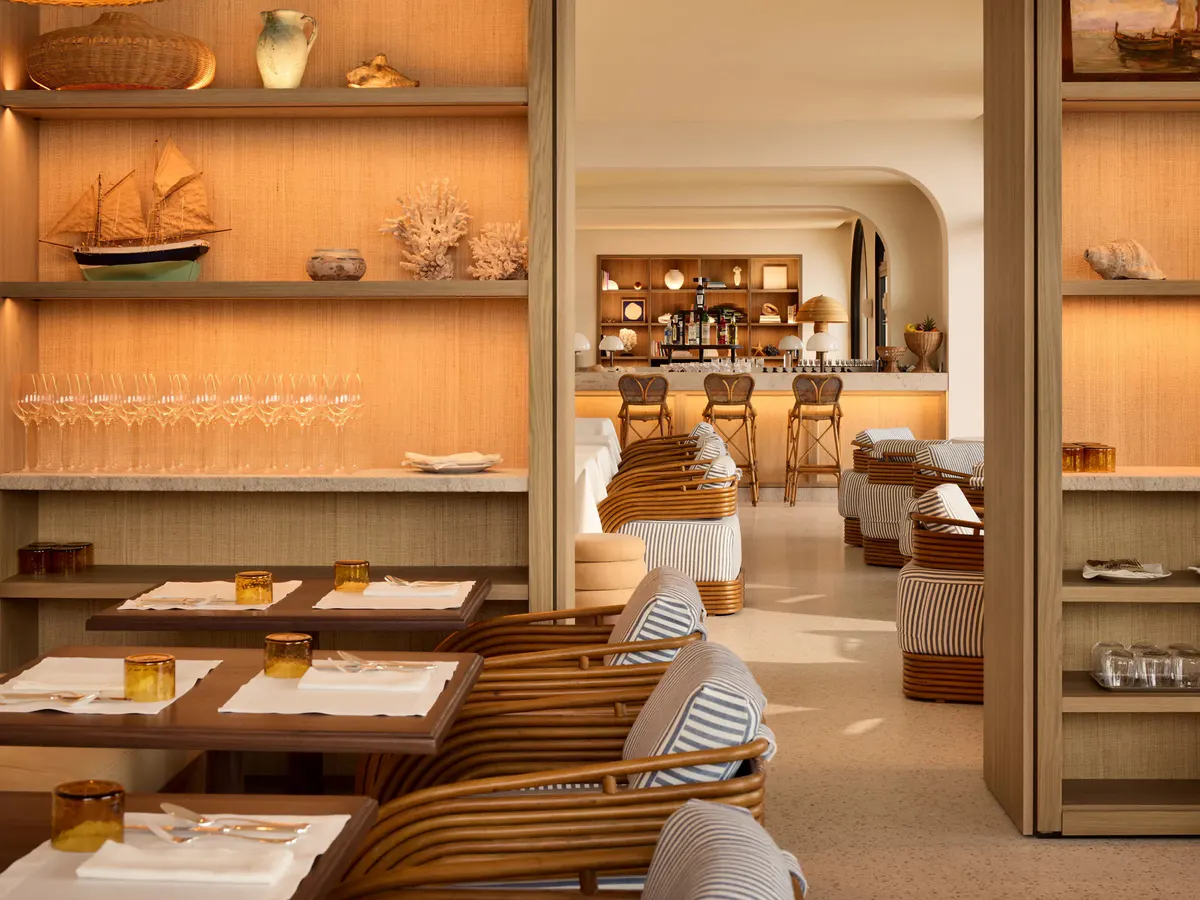 Model ships and coral sit on oak shelving between the dining room and bar beyond