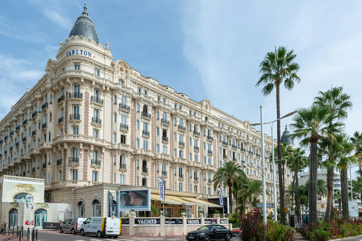 Exterior view of Carlton Cannes building on the Boulevard de la Croisette with palm trees and street below