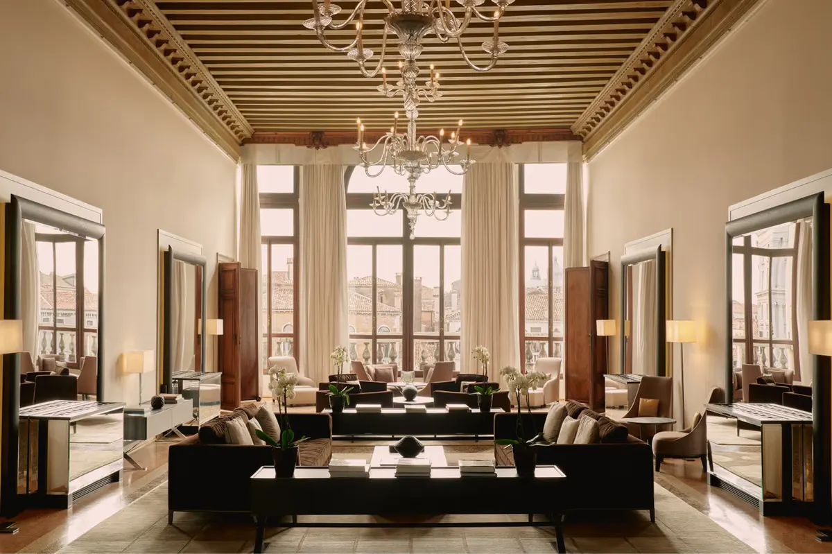 A luminous salon with a barrel-vaulted ceiling, tall arched windows, black upholstered seating, and marble flooring