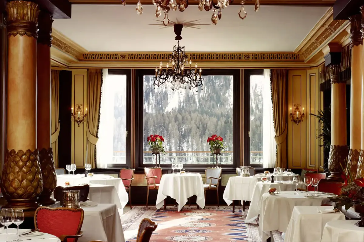 Formal dining room with gold trim, crystal chandelier, and mountain panorama