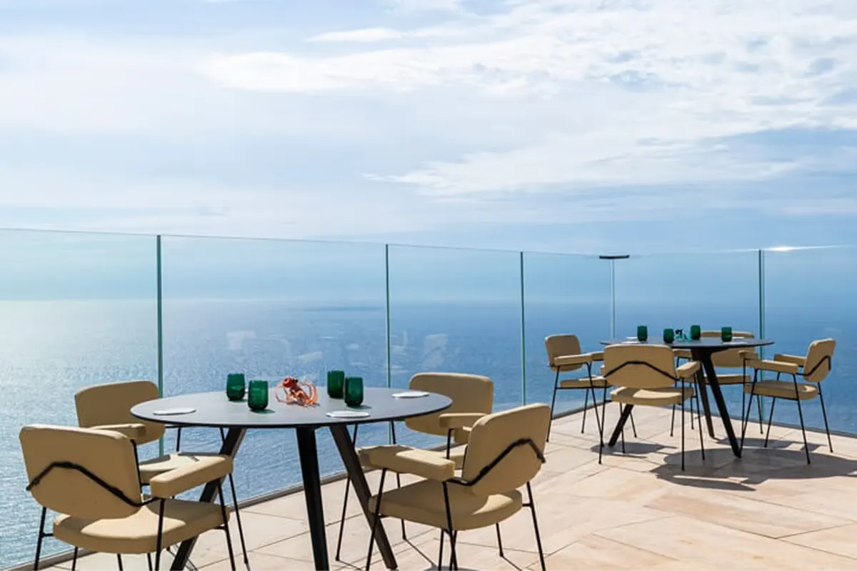 Outdoor dining with dark blue chairs overlooking the coast
