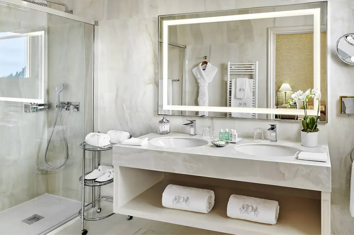 Modern white bathroom with double vanity and glass-enclosed shower