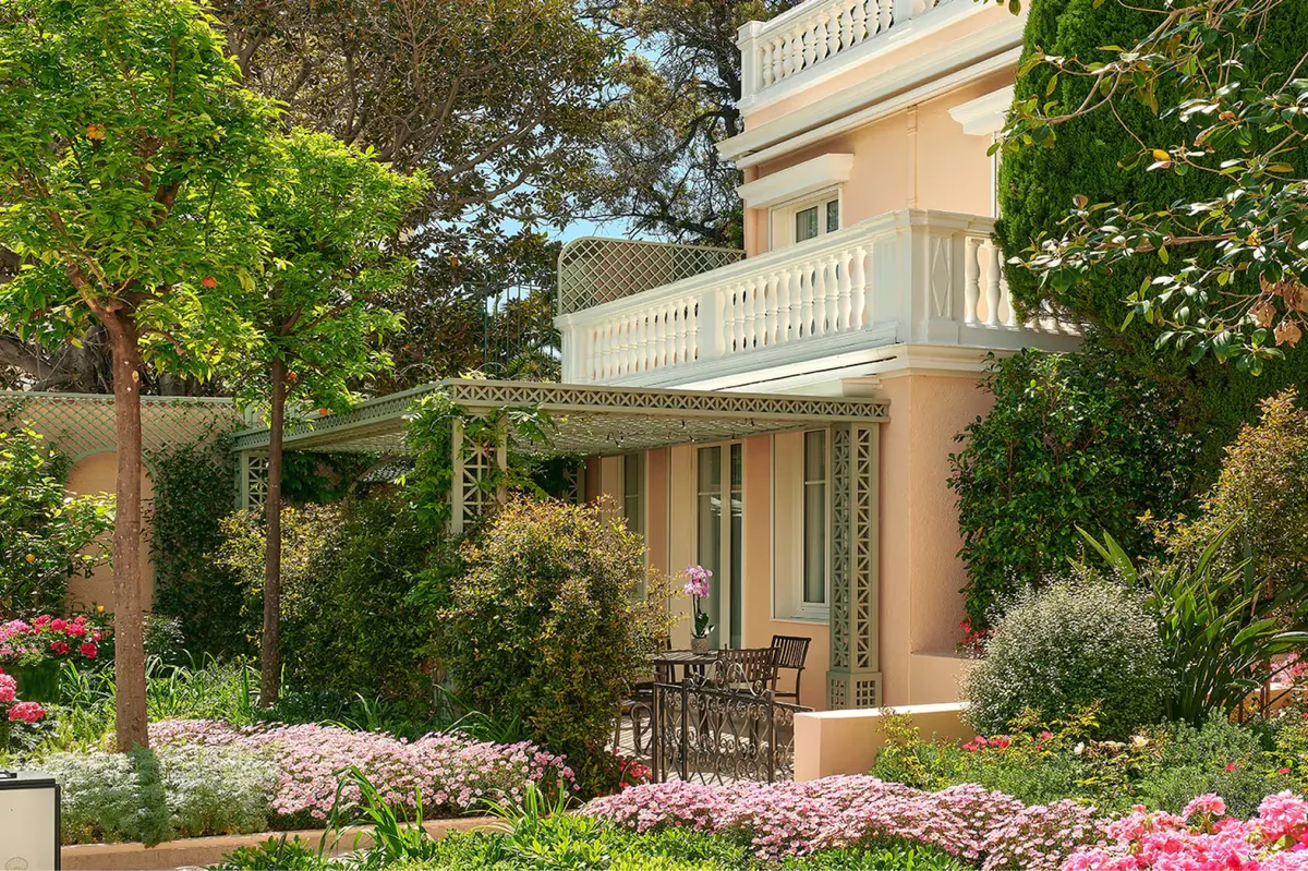 Exterior villa entrance surrounded by blooming pink and white flowers