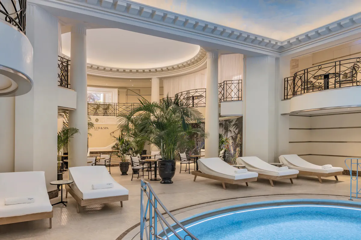 The spa lounge with indoor pool, arched alcoves, white loungers, and soft natural lighting