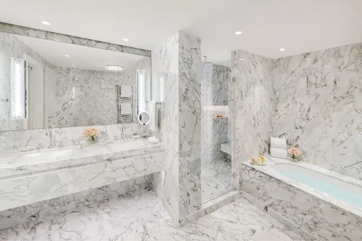Modern bathroom with marble cladding, walk-in shower, and double vanity